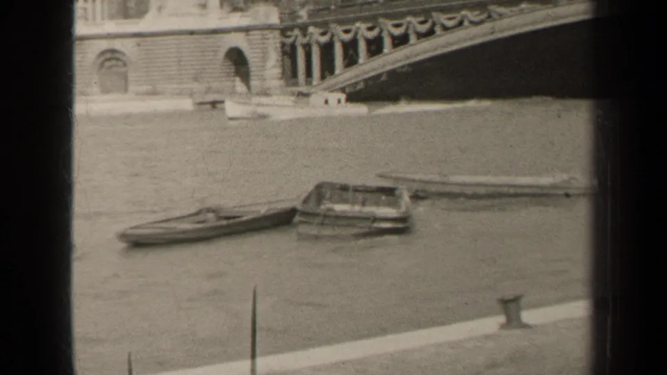 1947 Paris river scene with a small boat beside a floating platform and ornate bridge masonry behind.
