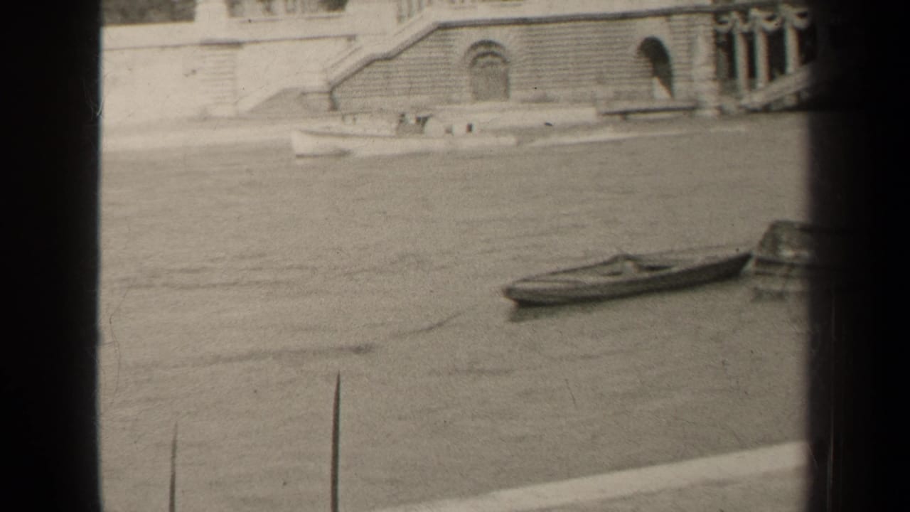 1947 Paris 8mm frame showing a small boat on river water below a stone embankment with arches, steps, and dark film borders.