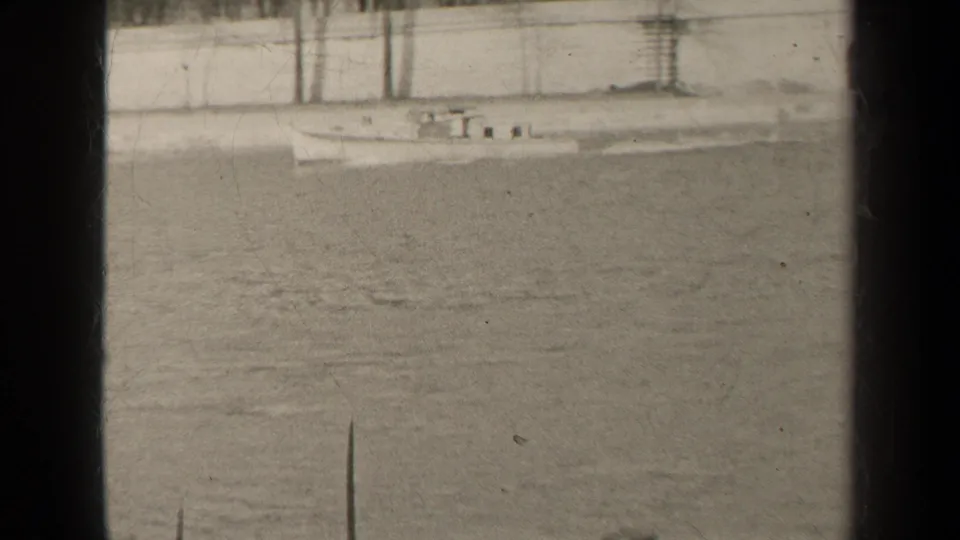 Final 1947 Paris 8mm frame showing a small boat beside a stone river embankment, with water, posts, and strong dark film borders.
