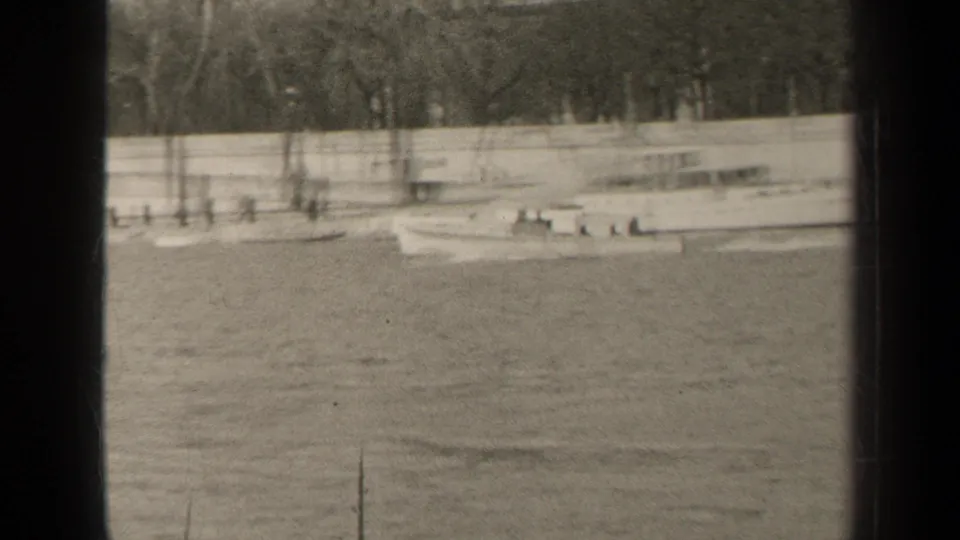 Final 1947 Paris frame showing the small boat farther along the water, with indistinct people, trees, and a low wall behind it.