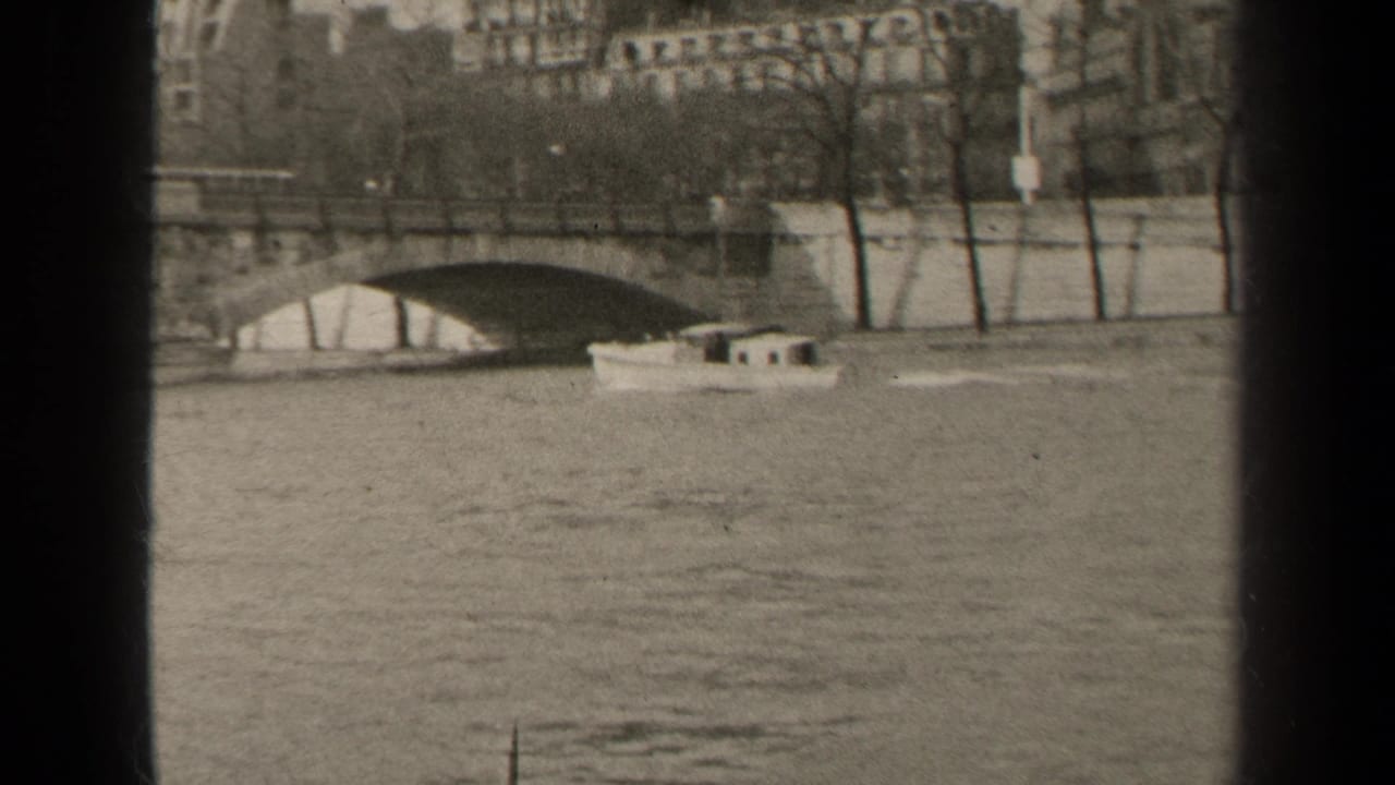 Small boat moving on the Seine near a stone arch bridge, seen through dark vertical frame edges.