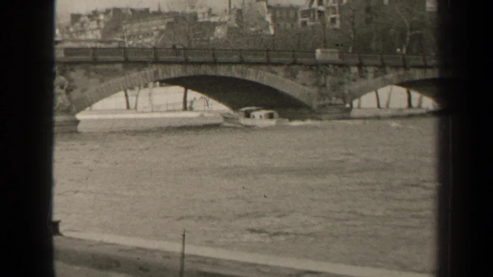 Final 1947 Paris frame showing river traffic near a stone Seine bridge, including a small cabin boat and a longer vessel.
