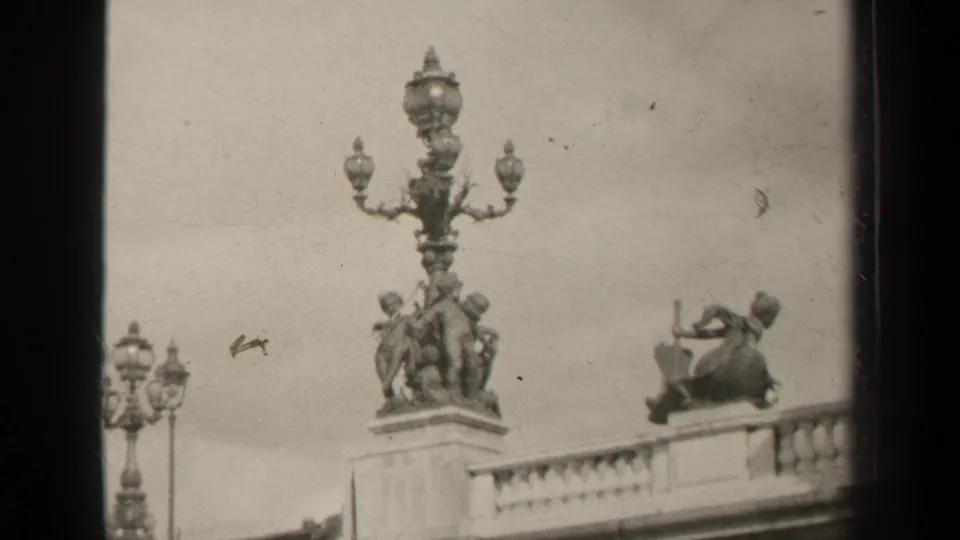 1947 Paris home-movie view of ornate lamps, sculptural bridge decoration, and a stone railing, framed with visible film wear.