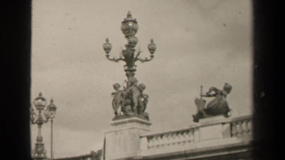 1947 Paris frame showing a tall decorative lamp, sculptural figures, smaller lamps, and a stone bridge balustrade.