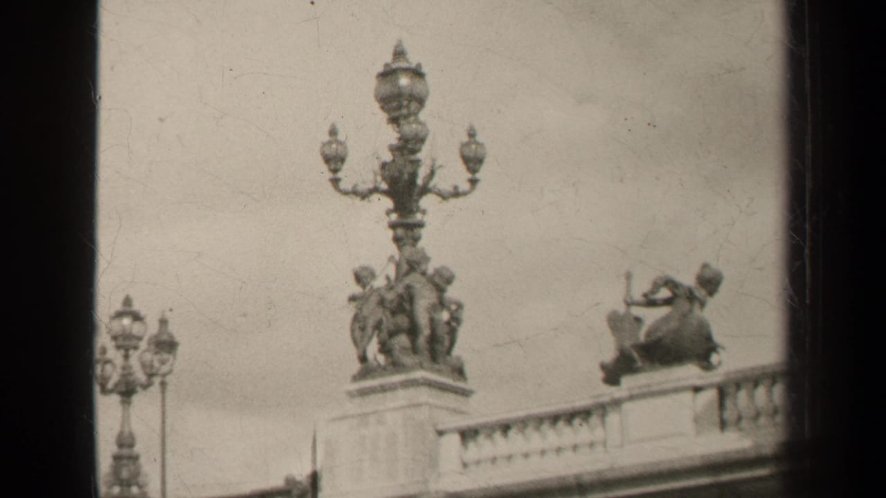 1947 Paris 8mm frame showing an ornate multi-globe lamp, classical sculptural figures, and a balcony balustrade.