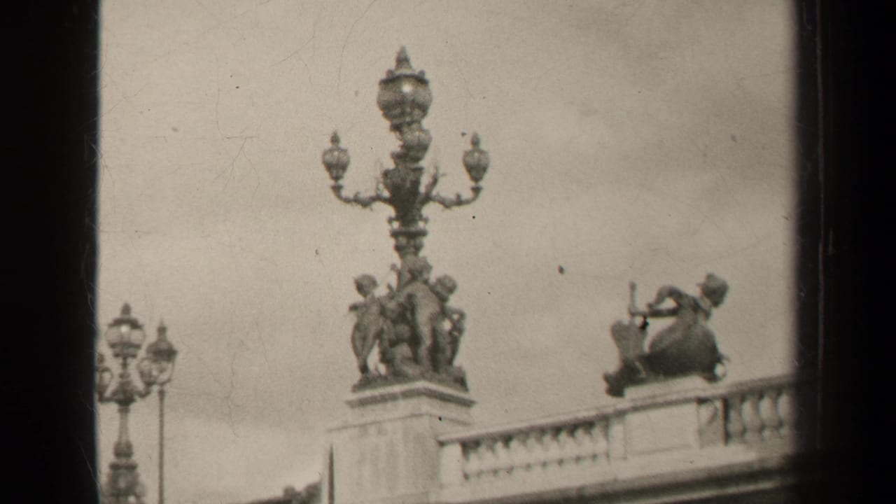 1947 Paris frame with ornate public sculpture, a seated musician-like figure, and a stone balcony rail.