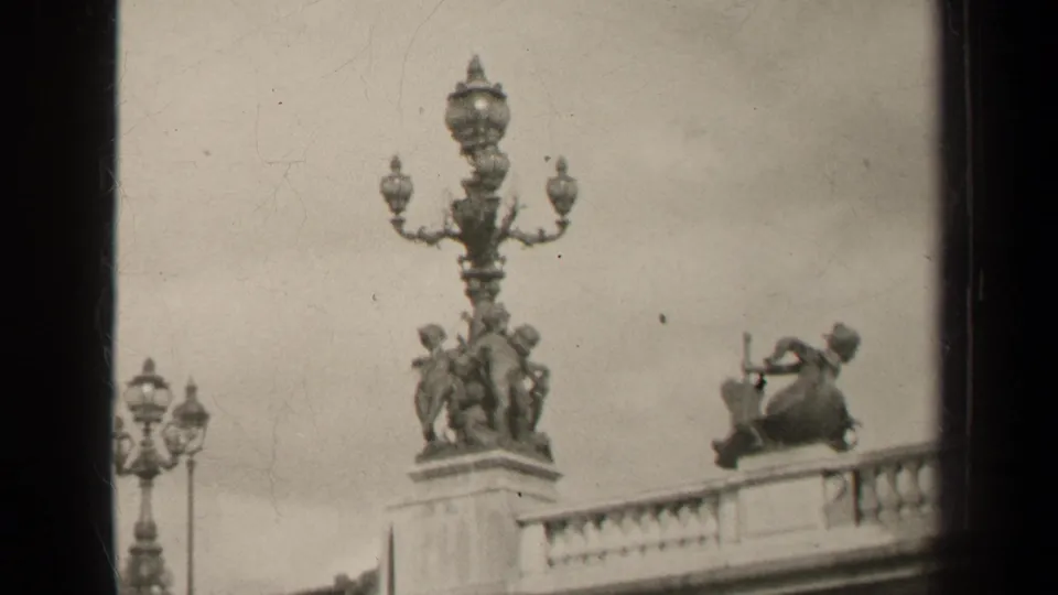 1947 Paris frame with ornate public sculpture, a seated musician-like figure, and a stone balcony rail.