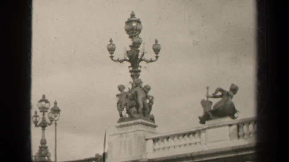 Black-and-white 1947 Paris 8mm view of sculptural figures, a tall decorative lamp, and balcony stonework.
