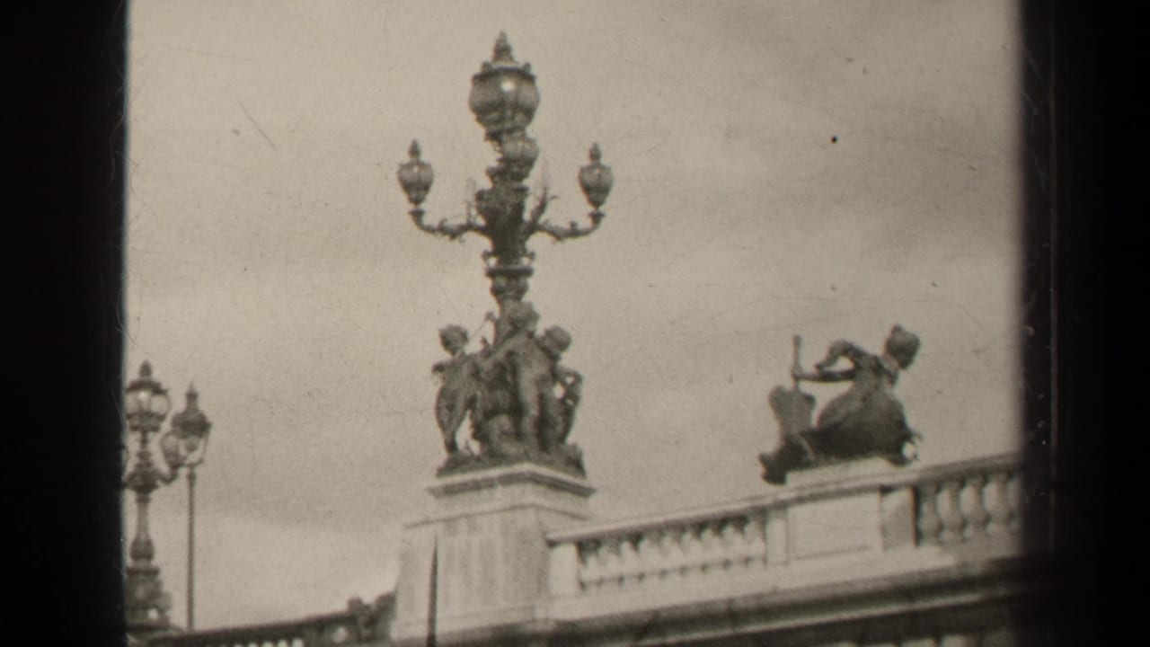 Ornate bridge lamppost and stone sculpture group above a balustrade.