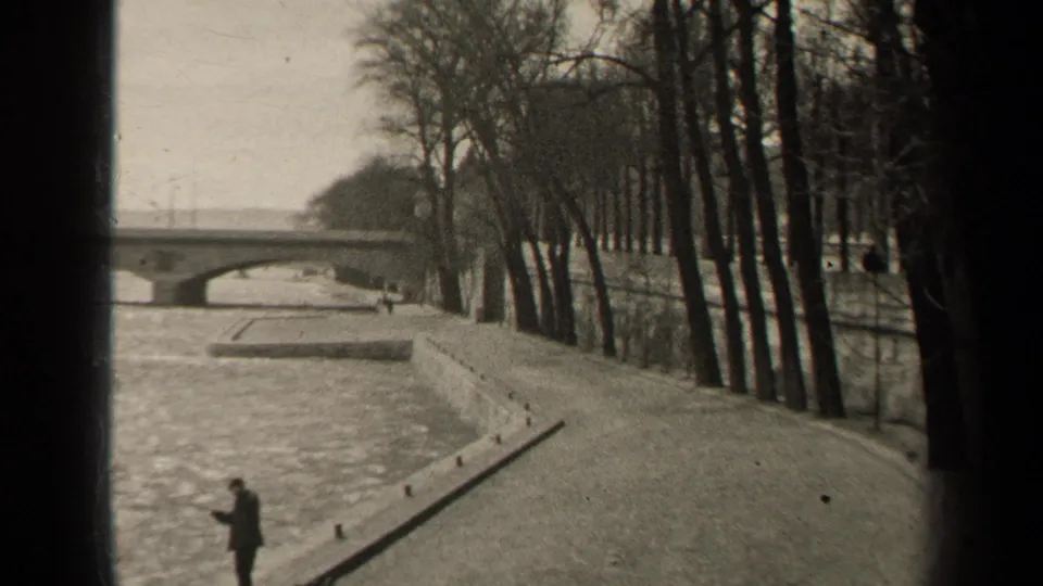 1947 Paris riverside scene with a solitary figure at the lower edge, a long embankment path, bare trees, and bridge arches in the distance.