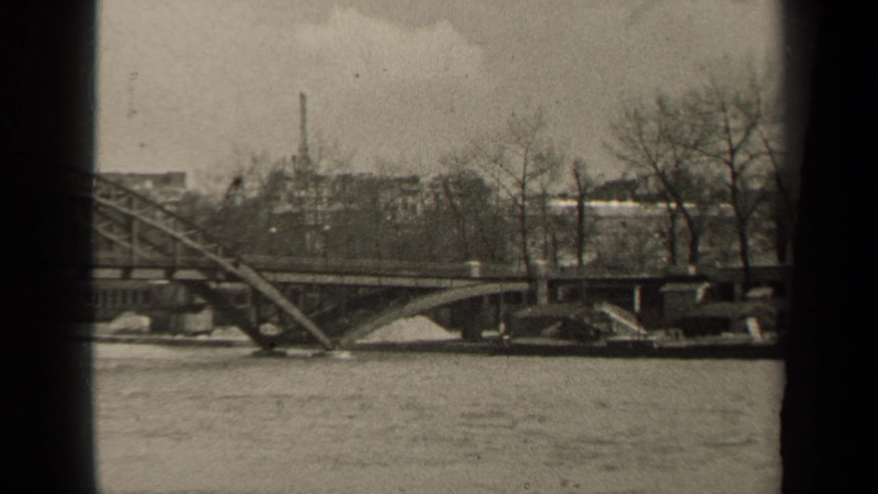 River bridge and tree-lined embankment seen through dark film-frame edges.