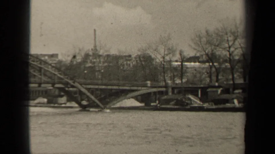 Black-and-white 1947 Paris frame with the bridge, river surface, bare trees, distant buildings, and visible vertical film-gate edges.