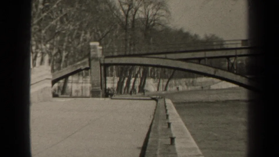 1947 Paris frame showing a bridge over or beside the river, with a stone embankment, walkway, and leafless trees in view.