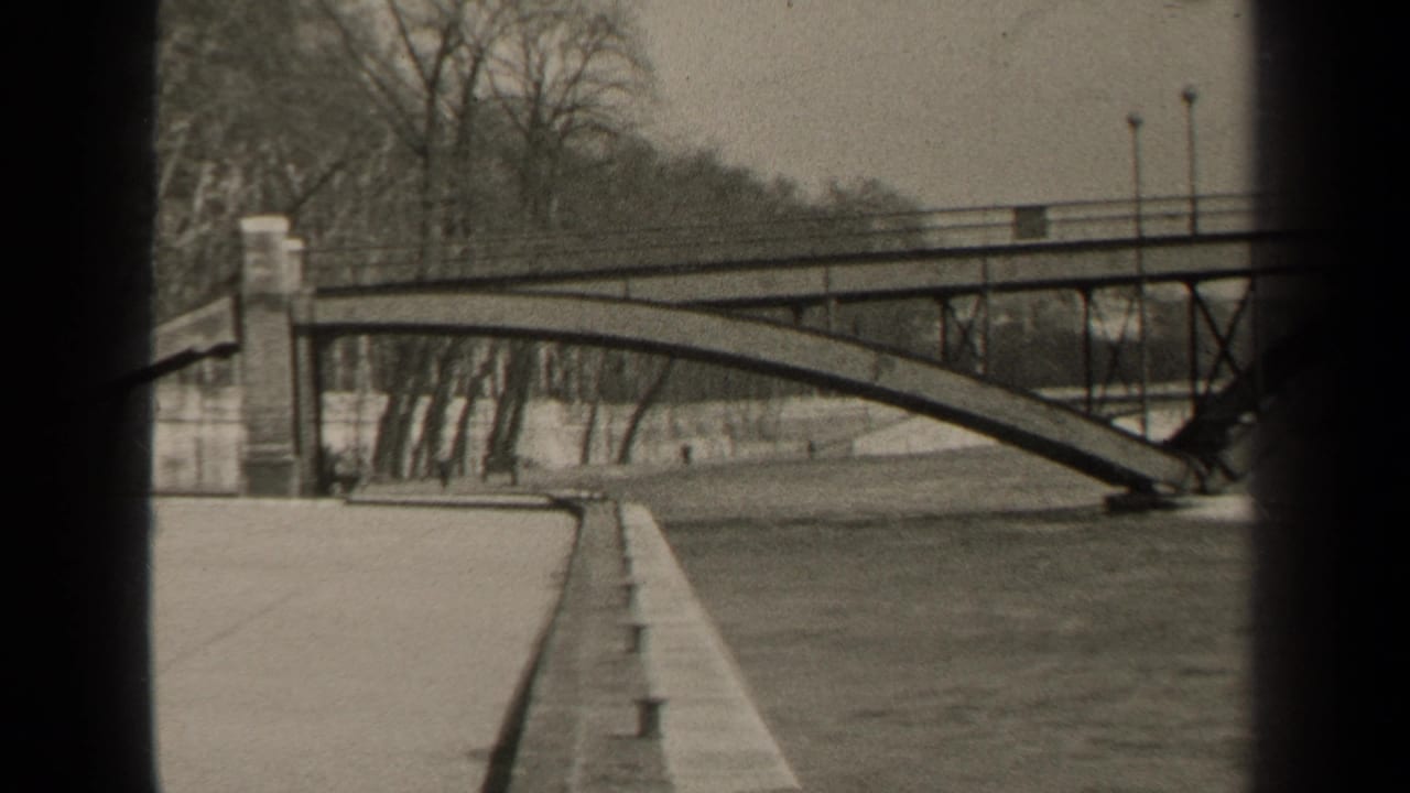 Arched bridge over a wide river with bare trees and dark frame edges.