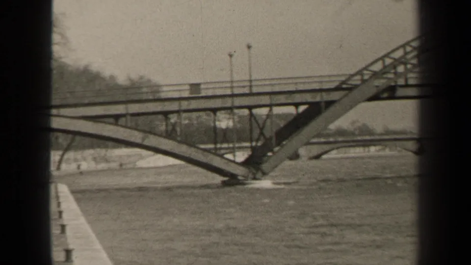 1947 Paris view of a metal arched bridge span over a broad river, with lamps along the deck and another bridge faintly beyond.