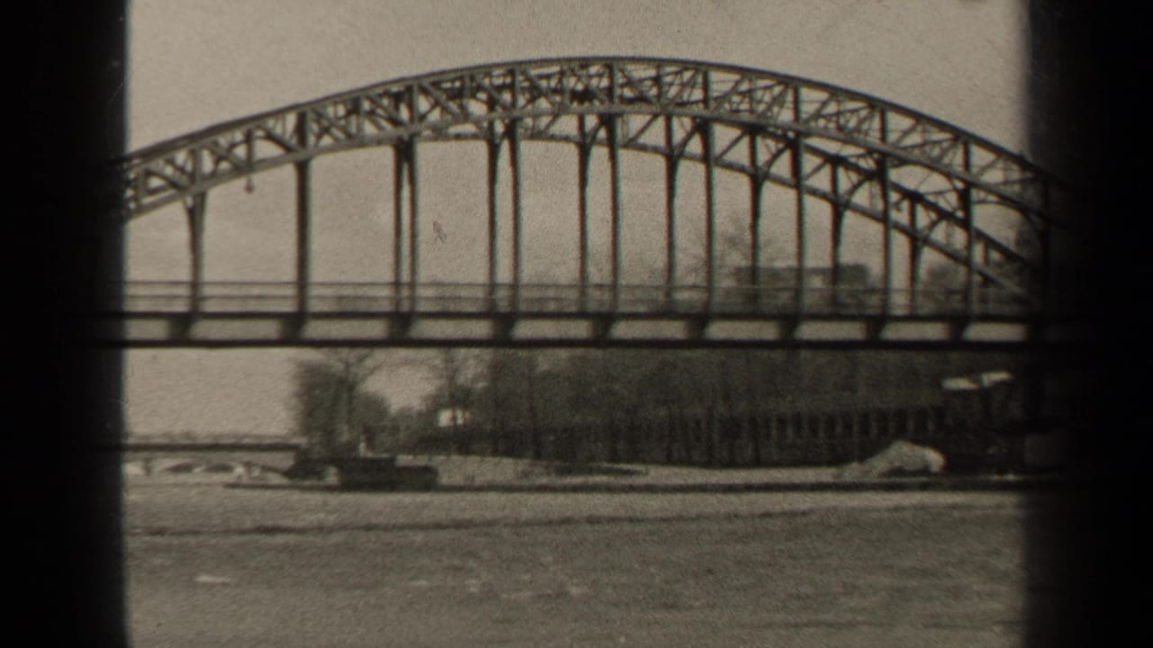 1947 Paris frame with the bridge span centered over the river, showing its arched truss and a quiet tree-lined bank.