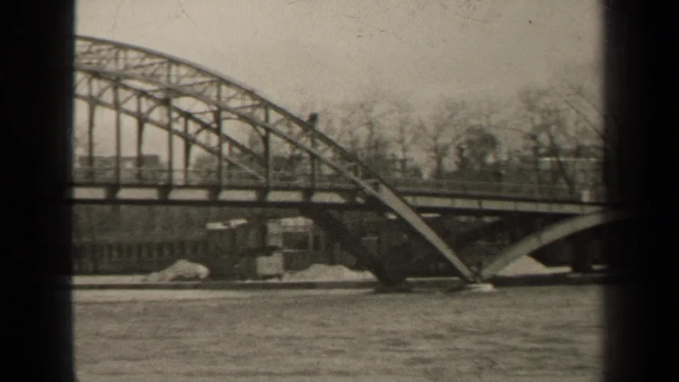 1947 Paris frame showing the bridge arch near the riverbank, with bare trees, embankment details, and visible 8mm frame edges.