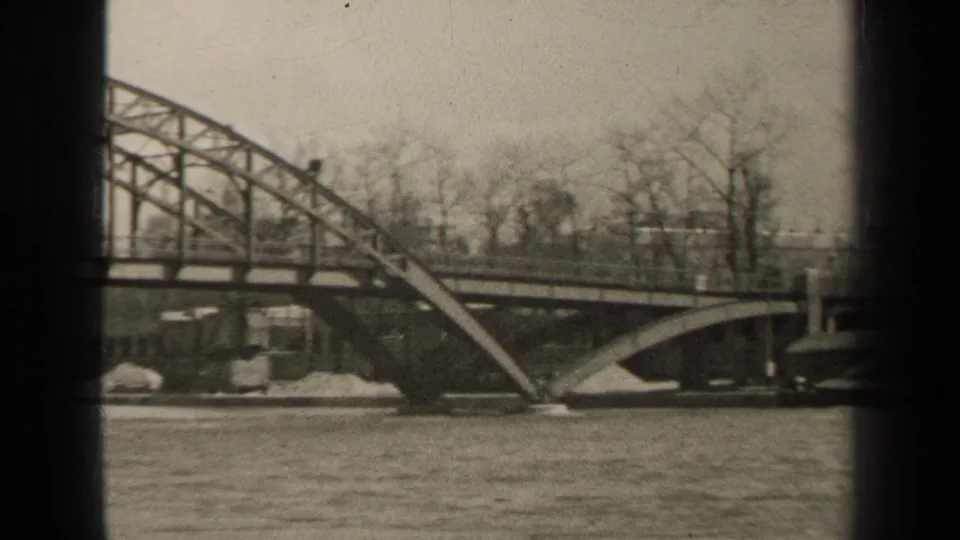 Black-and-white 1947 Paris river view with fast water, arched bridge structure, bare winter trees, and dark 8mm frame edges.