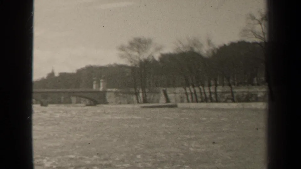 1947 Paris 8mm frame with a soft-focus river, bridge, bare trees, and raised far bank.