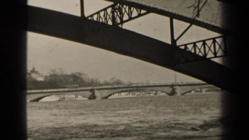 1947 Paris view from near a bridge, looking across a flowing river toward a distant stone arch bridge.