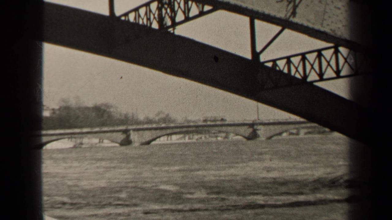 River and arched bridge seen through dark bridge supports.