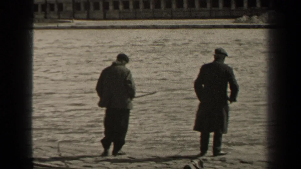 1947 Paris riverside frame with two men in coats and hats standing by the water, one with a fishing rod, and a bridge across the far bank.