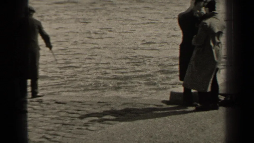 1947 Paris riverside frame with several adults gathered near the bank while a man with a fishing rod stands closer to the water.
