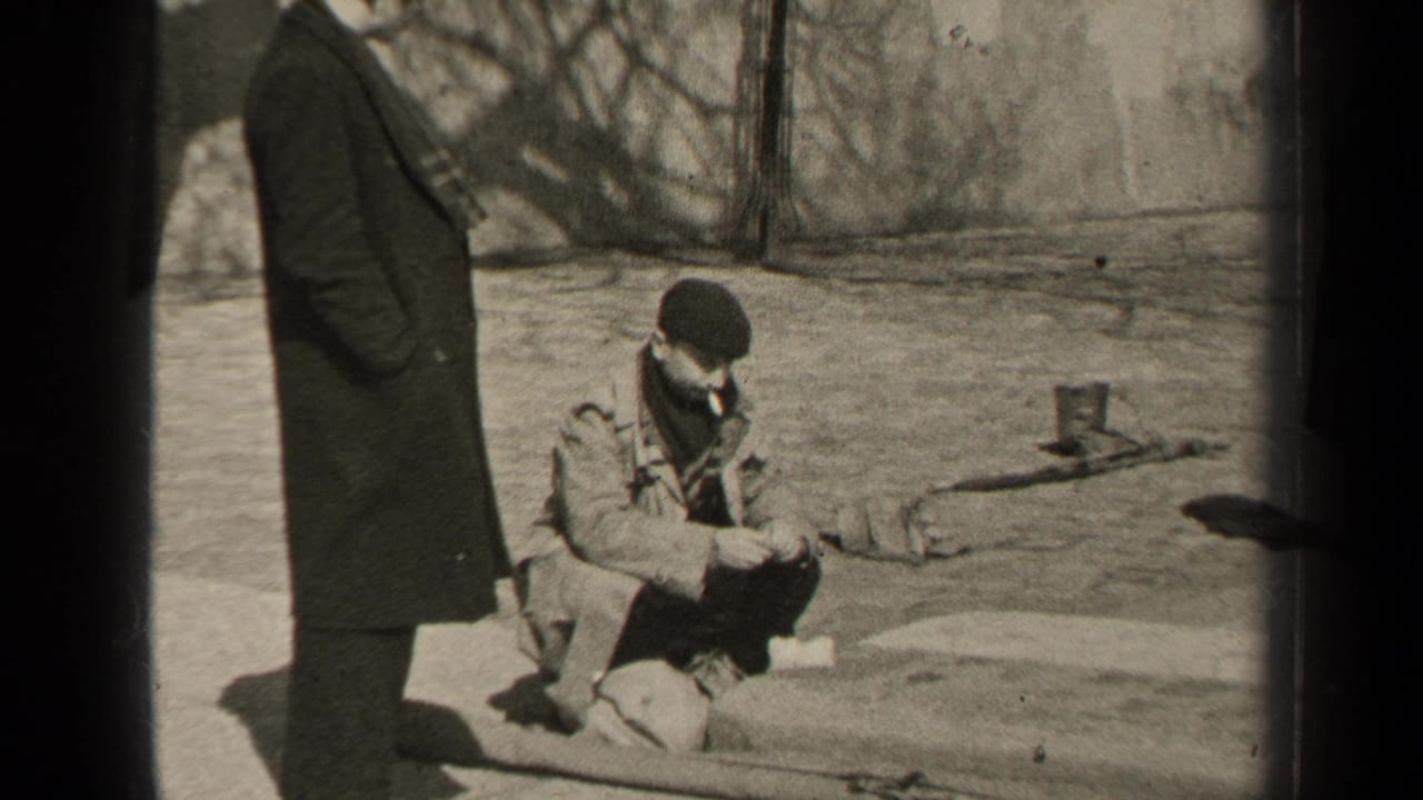 In 1947 Paris, two adult men pause outdoors in winter coats, with one crouched on a stone ledge smoking while another stands nearby.