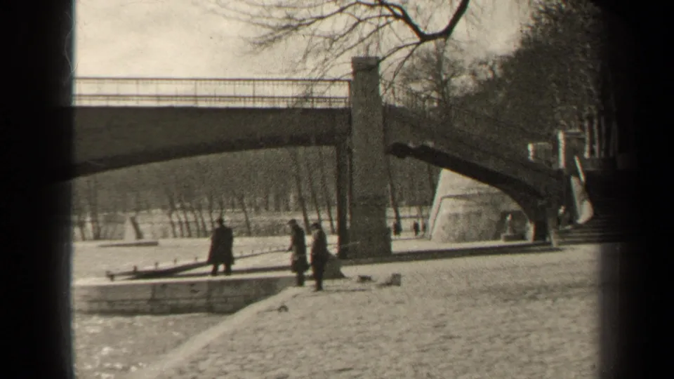 A 1947 Paris riverside view shows several pedestrians near a stone bridge support and cobblestone embankment.