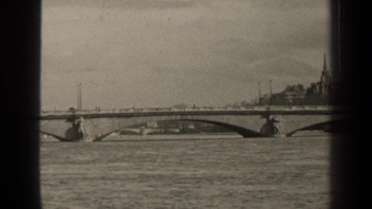 Black-and-white Paris river scene showing an arched bridge across the water, distant buildings, a church spire, and small figures on the bridge.