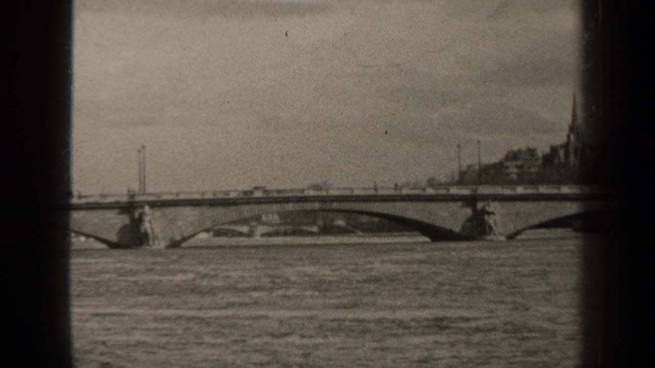 1947 Paris frame of traffic moving across a long arch bridge over water, with soft focus and dark 8mm frame borders.