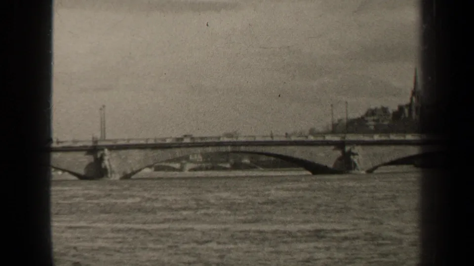 1947 Paris frame of traffic moving across a long arch bridge over water, with soft focus and dark 8mm frame borders.