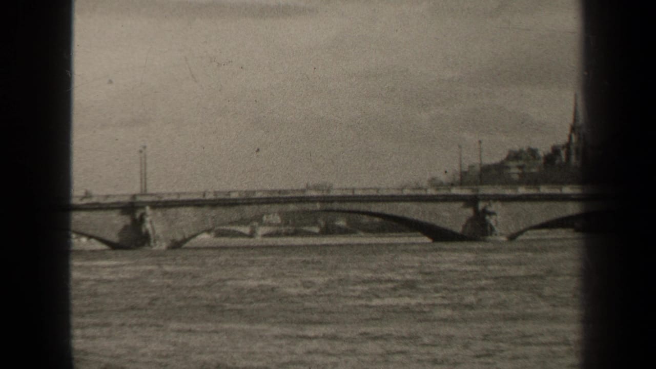 Arched bridge over water with a distant structure and film edge shadows.