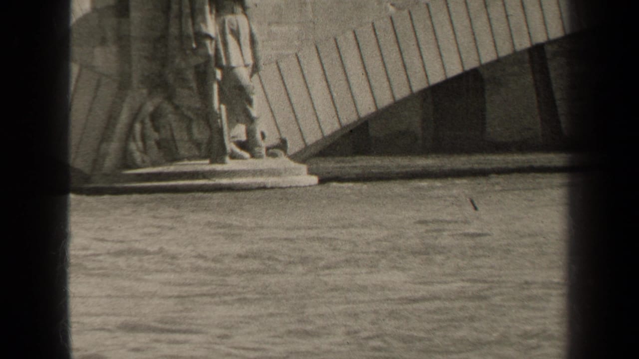 1947 Paris waterside view with gentle waves below a carved stone statue base and curved architectural element.