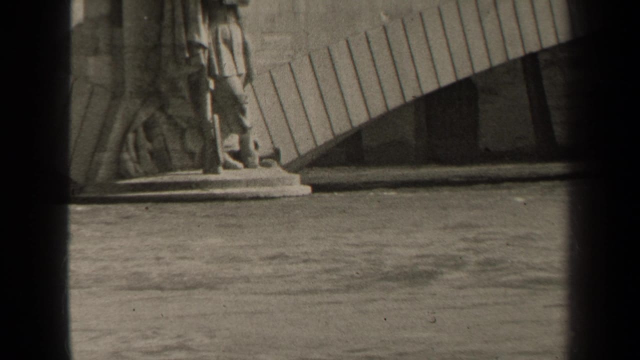 1947 Paris home-movie frame showing floodwater near a stone bridge, with a sculptural bridge support visible at the left.