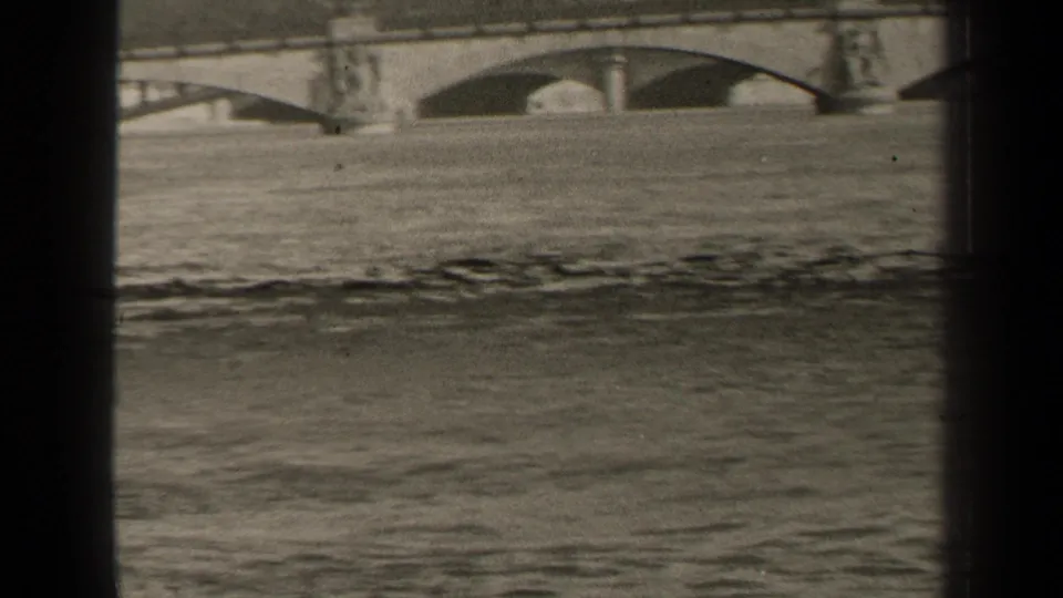 1947 Paris frame showing a stone bridge and sculptural pier above floodwater, framed by dark 8mm film borders.