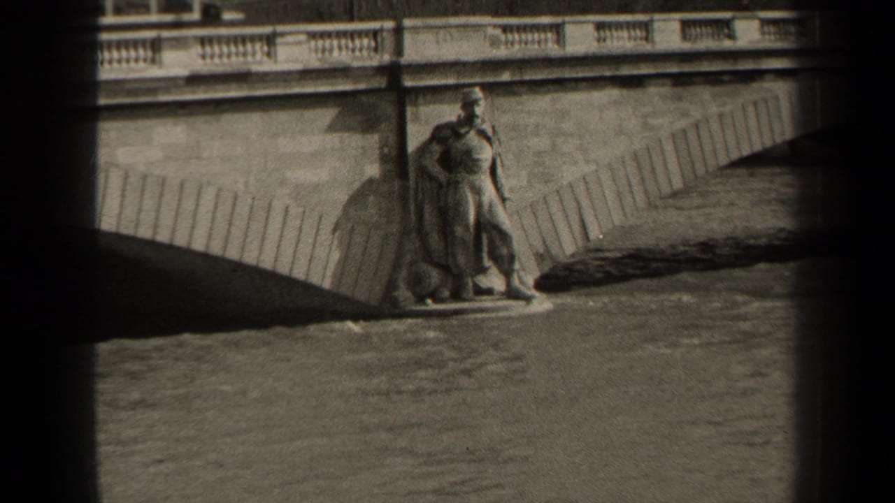 1947 Paris home-movie frame showing a riverside soldier-like statue, stone bridge railing, arch shadow, and water below.