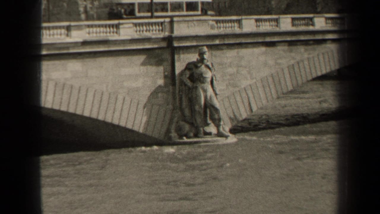 Riverside statue at the base of a bridge, with water and a dark arch shadow nearby.