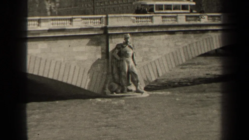 Grainy 1947 Paris frame showing the riverside statue, stone bridge structure, balustrade, and water under the arch.