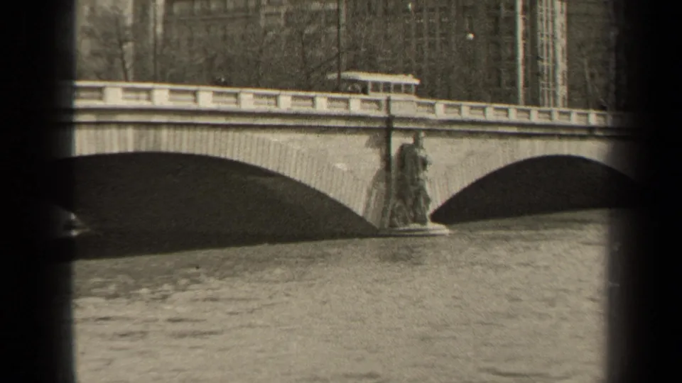 The camera view shifts along the Paris bridge, showing the trolley partly hidden behind the balustrade and a statue-like pier detail.
