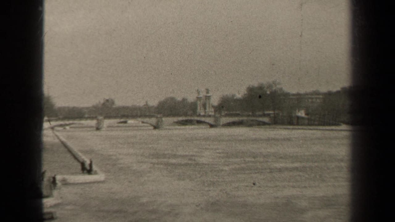 1947 8mm home-movie frame of a Paris waterway with a multi-arched bridge, embankment edge, distant trees, and soft grain.