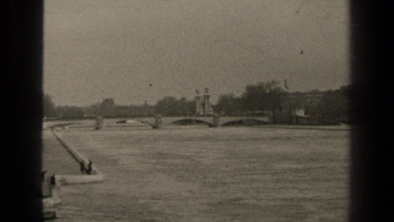 Vintage 8mm Paris frame showing the river, arched bridge, central pier ornament, distant trees, and dark vertical film border.