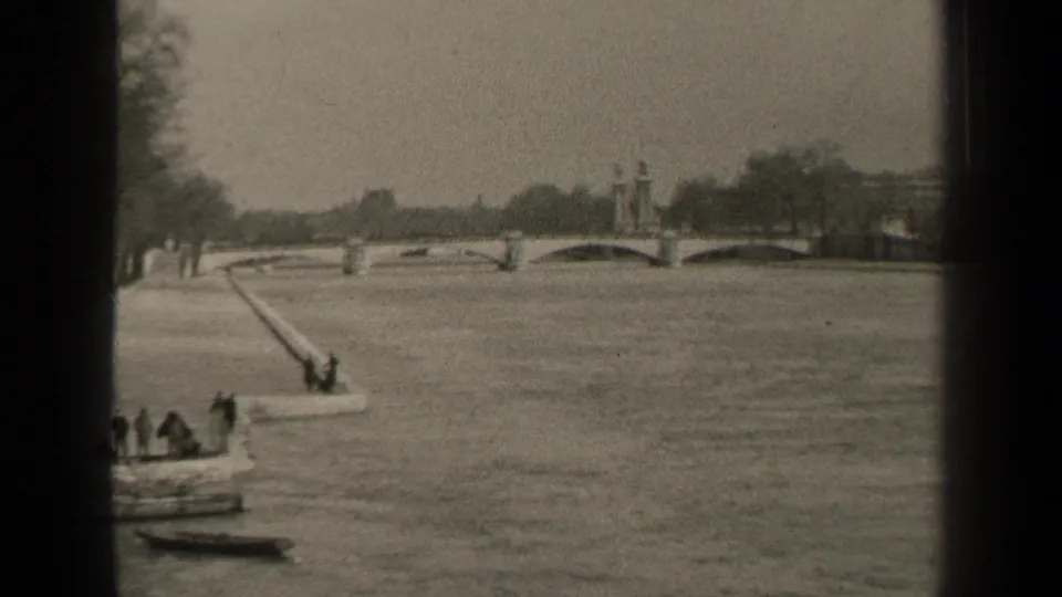 1947 Paris river view with an arched bridge, long ramp into the water, small craft, and distant people along the bank.