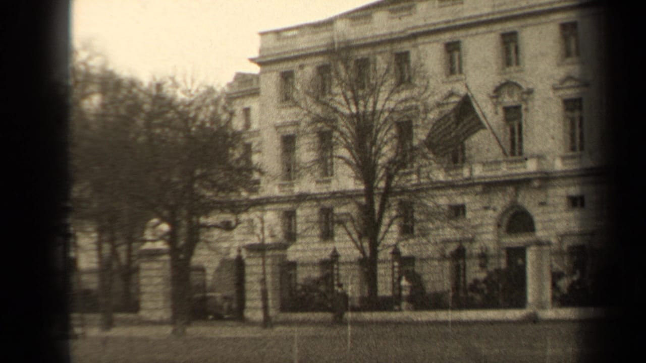 1947 Paris street view of a large classical building, bare trees, fence, pedestrians, and a U.S. flag on the facade.