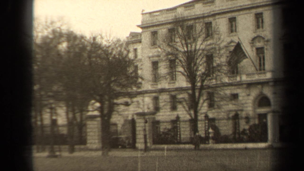 Paris 1947 exterior view of a classical facade with a blowing U.S. flag, bare trees, fence, and small pedestrians.