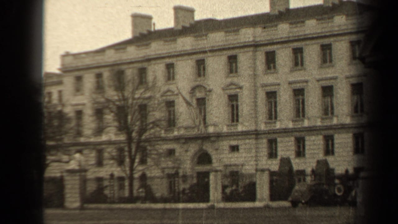1947 Paris home-movie frame showing a pale classical facade, rows of windows, a bare tree, and cars near the curb.
