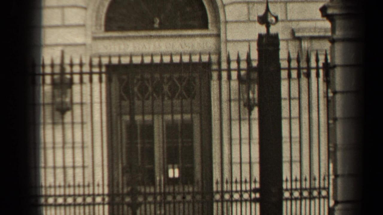 1947 Paris home-movie view of a gated stone building, centered on the fence, window bars, and masonry details.