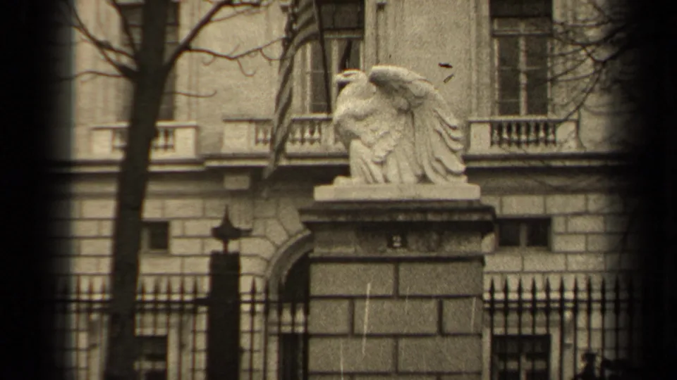 1947 Paris view of a stone eagle sculpture atop a masonry pillar, with iron fencing and a classical facade behind it.