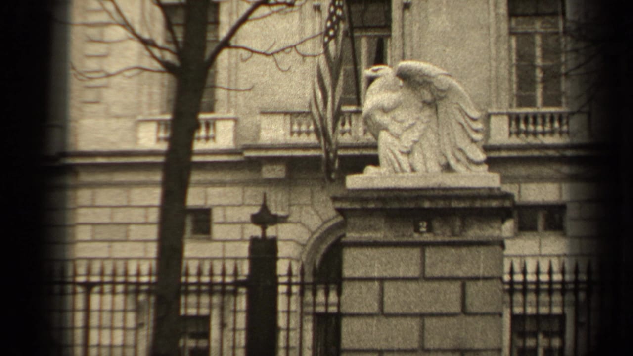 1947 Paris 8mm frame showing a stone eagle on a pedestal outside a formal stone building, partly framed by bare trees and an iron fence.