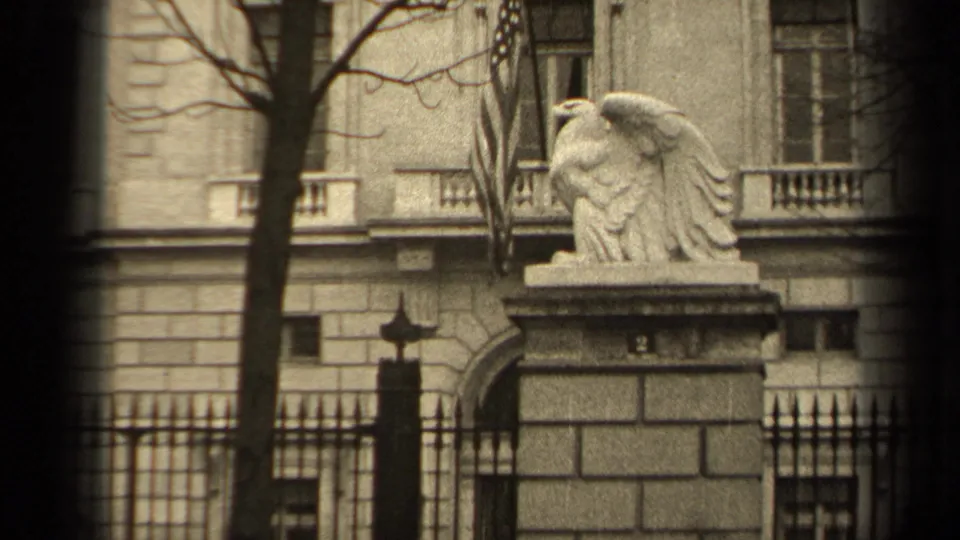 1947 Paris 8mm frame showing a stone eagle on a pedestal outside a formal stone building, partly framed by bare trees and an iron fence.